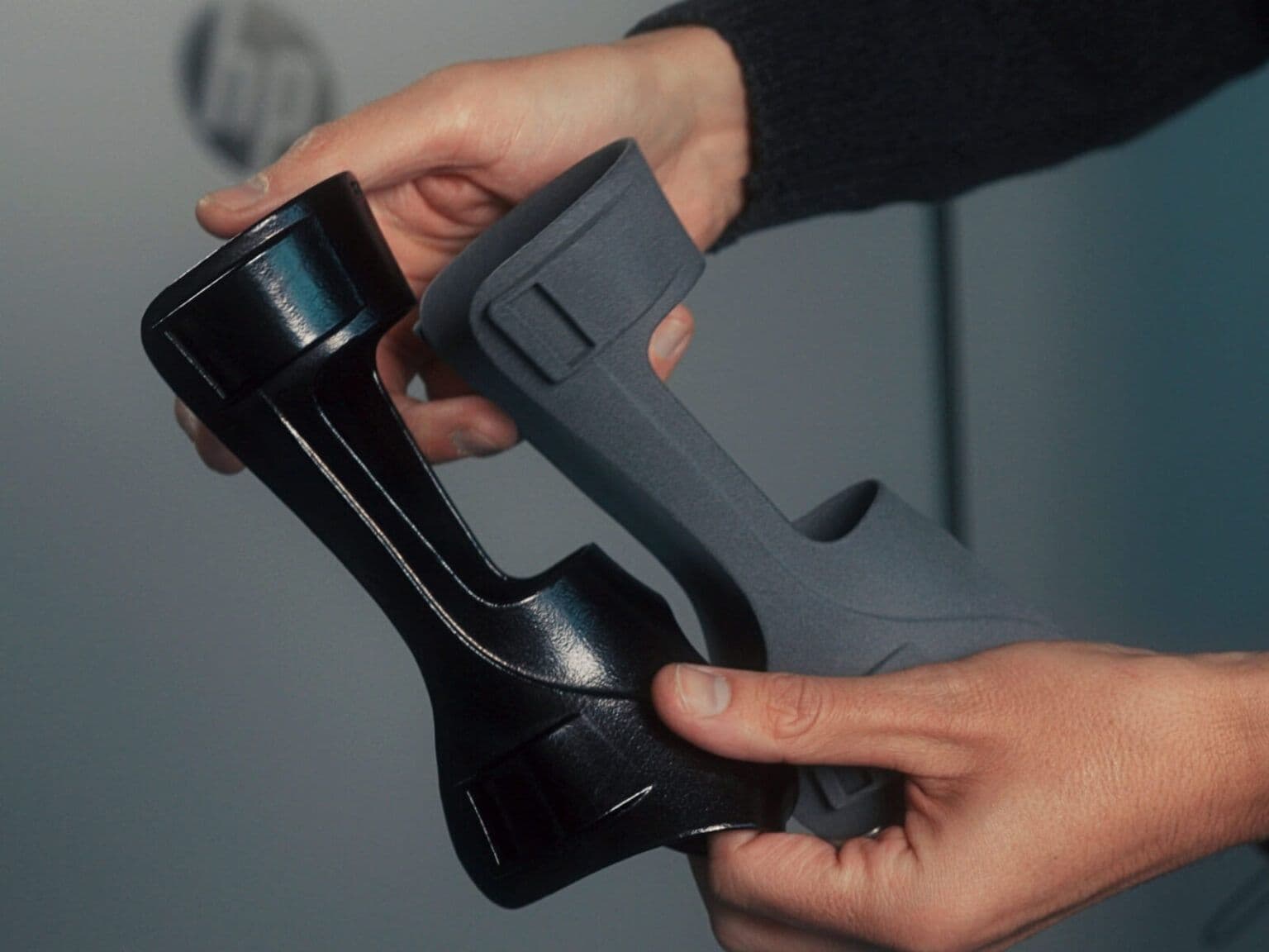 A pair of hands holding two 3d printed objects.