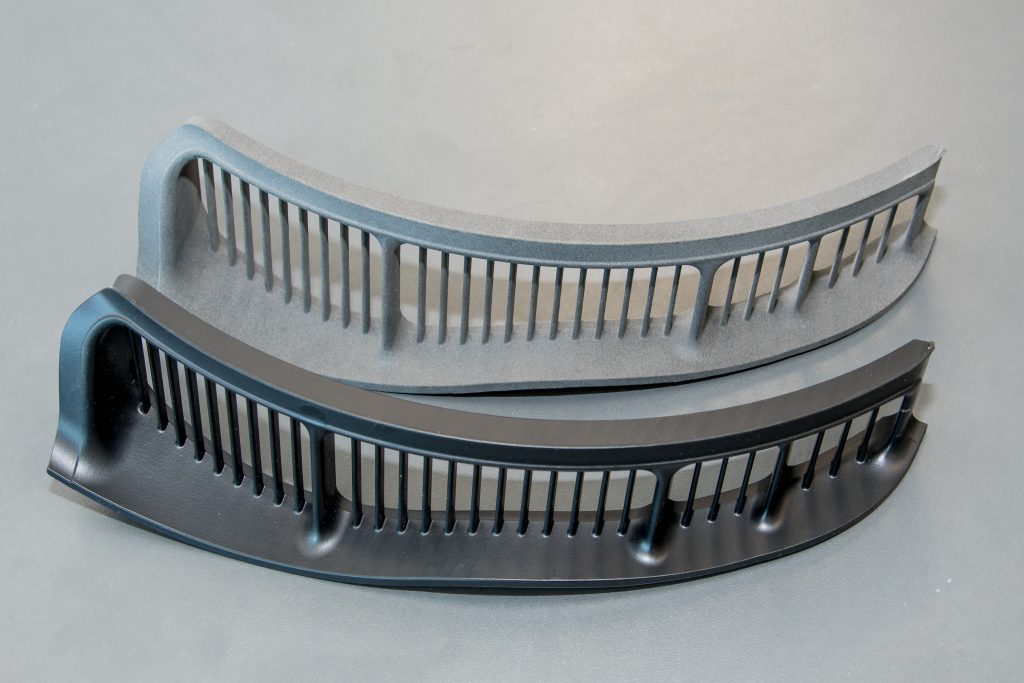 Two 3D printed grills. Both grey with one darker than the other. Both components are slightly curved.