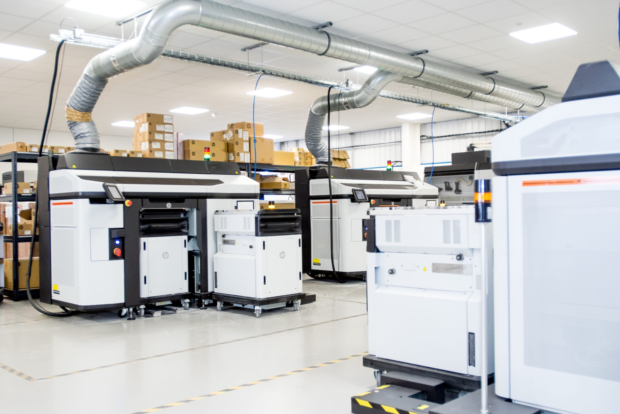 A factory floor showing three HP 3D printers.
