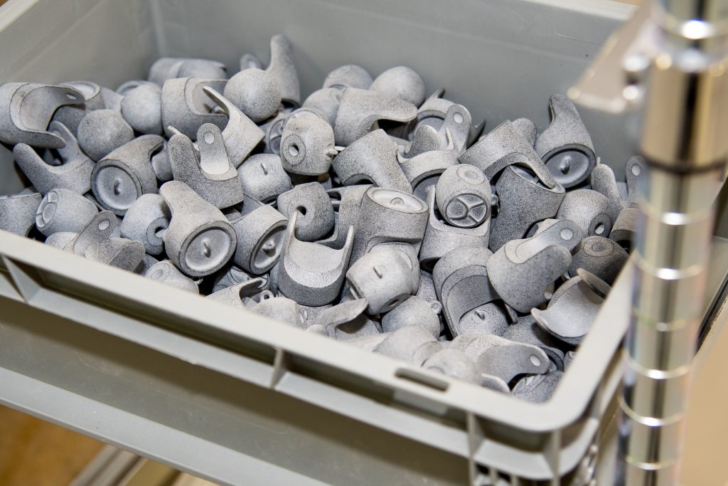 A stack of white nylon parts fresh from a powder build, still showing their raw surface.