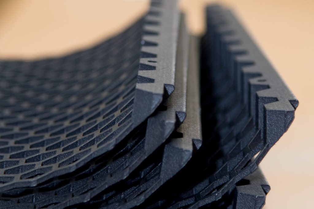 A stack of five 3D printed components, each a black curved honeycomb structure.