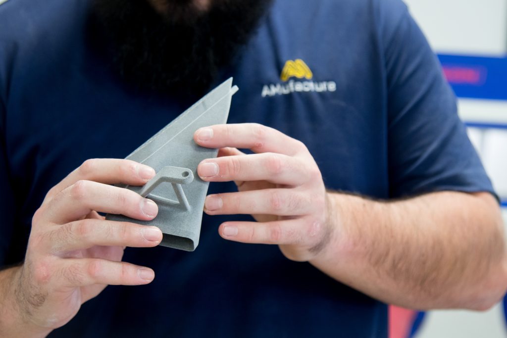 An AMufacture engineer holding a 3D-printed nylon bracket