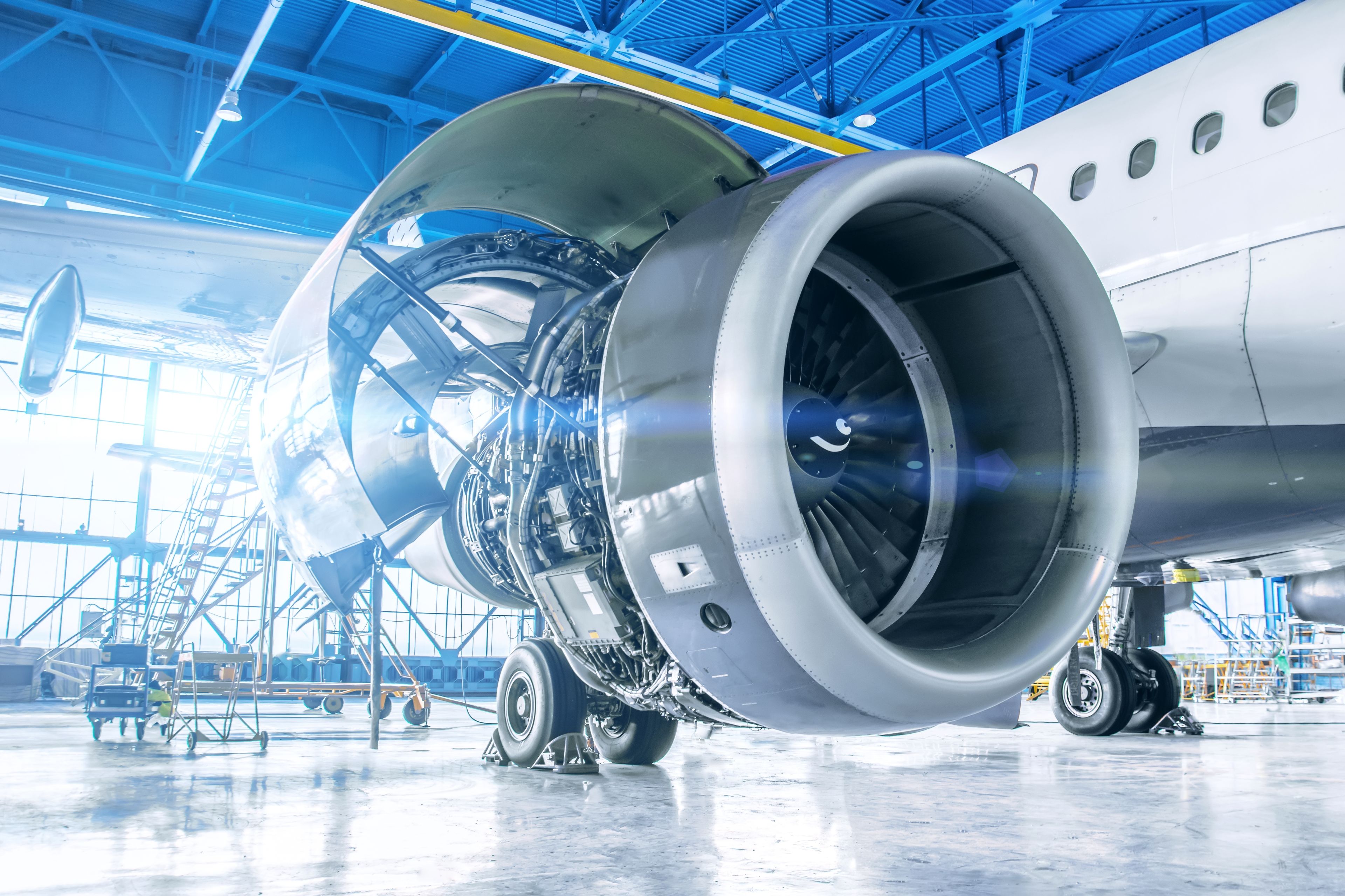 A commercial aircraft jet engine with its cowling open during maintenance in a hangar