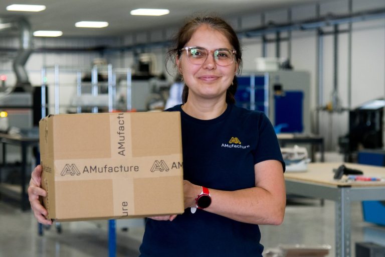 AMufacture team member holding a branded parcel on the production floor